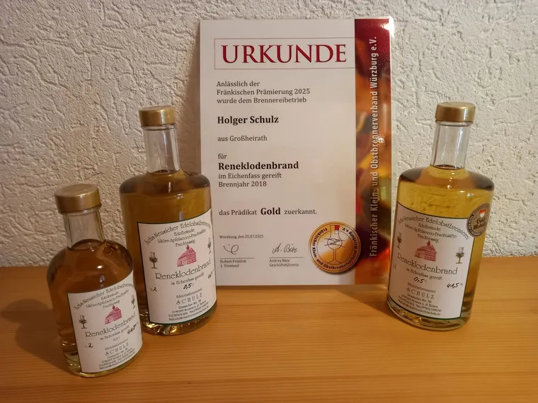Goldurkunde für den Reneklodenbrand neben zwei Flaschen