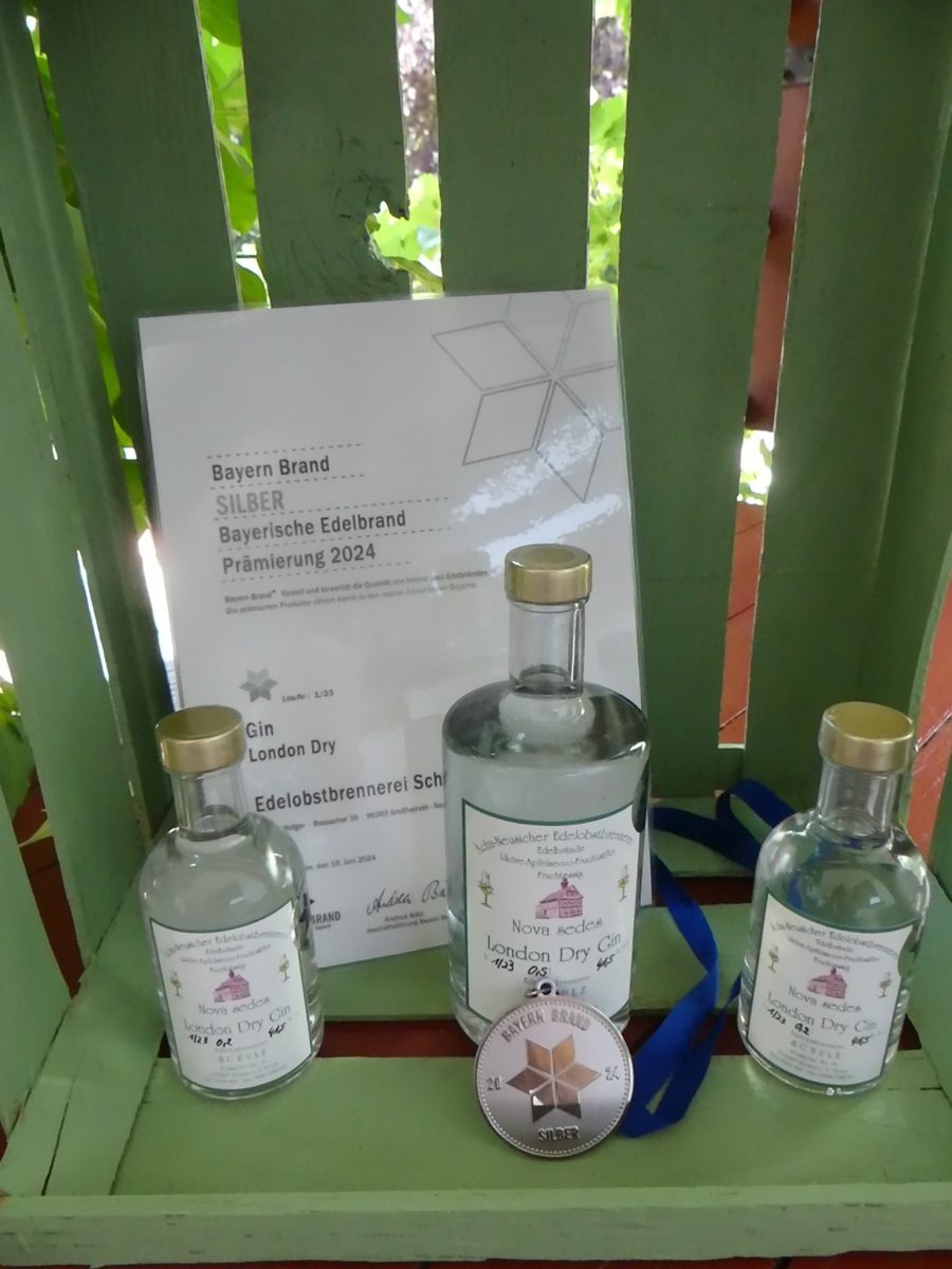 Drei Flaschen London Dry Gin vor der Silber-Urkunde